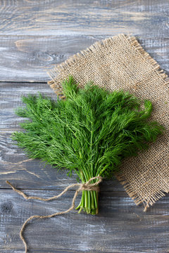 Bunch of fresh dill on a wooden surface with free space. Rustic style, selective focus