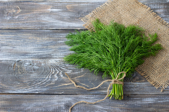 Bunch of fresh dill on a wooden surface with free space. Rustic style, selective focus