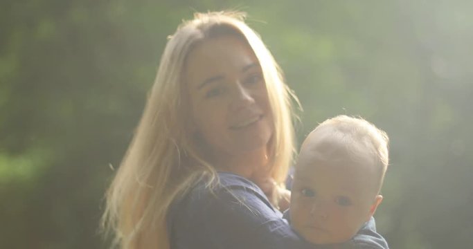 Beautiful young mother holding adorable cute child smiling outdoor playing summer sunny son infant toddler parent motherhood little boy native smile mom woman happy kid childhood hug hugging hugs baby