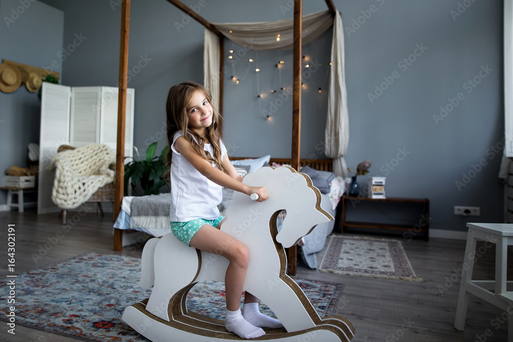 Wall mural Cute little girl riding a toy horse