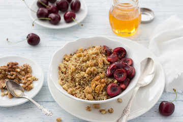 Healthy delicious vegan breakfast. Quinoa with fresh cherries, walnuts and honey on the blue background