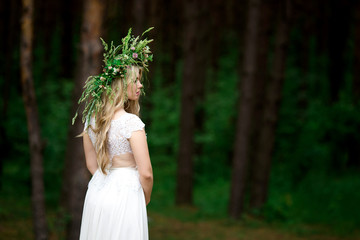 Portrait of a beautiful bride in a white dress and a wreath of Forest flowers