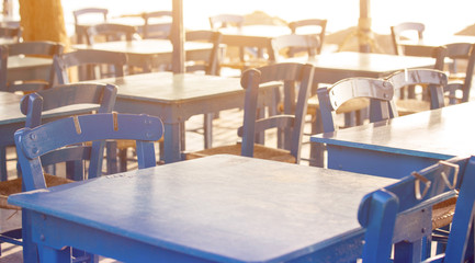 Fototapeta na wymiar Tables and chairs in a street restaurant in Kamari on Santorini