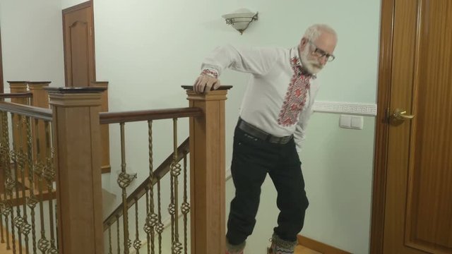 Old gray-haired man up the stairs at home