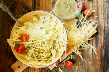 Tagliatelle pasta with pesto sauce and basil leafs on white plate, white wood background, top view