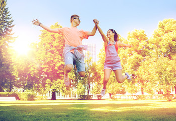 happy teenage couple jumping at summer park