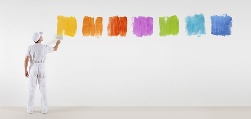 painter man with paint brush painting color samples isolated on blank white wall background, web...