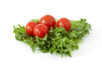Several cherry tomatoes on fresh lettuce leaves on a white background
