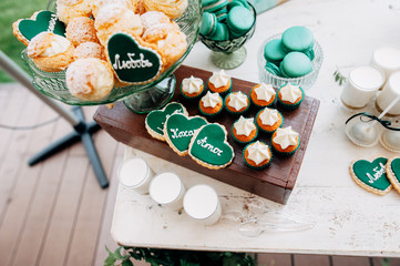 green sweet bar with muffins cakes and sweets in area of wedding party