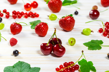 Colorful delicious fresh fruit strawberries, cherries, currants and raspberries on white wooden background. Beautiful, delightful and healthy desserts