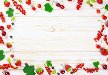 Colorful delicious fresh fruit strawberries, cherries, currants and raspberries on white wooden background. Beautiful, delightful and healthy desserts