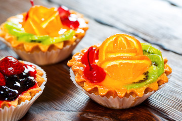 Delicious fruit cake on brown wooden background with strawberries, cherries, currants and raspberries. Beautiful, delightful and healthy desserts