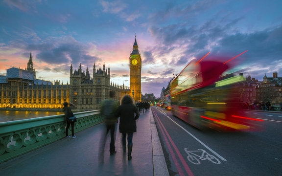 London, England - Iconic Red Double Decker Bus on the move on Westminster Bridge with Big Ben and Houses of Parliament at background. Sunset with beautiful colorful sky