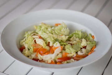 A white plate with tomatoes, carrot, cucumber and lettuce.