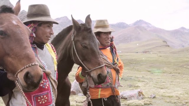 Peruvian men wearing a highlander hats near horses on the mountains of Peru.