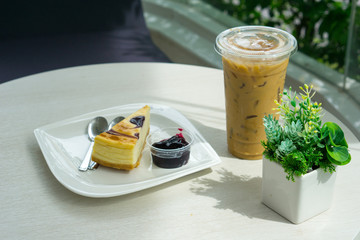 Obraz na płótnie Canvas iced coffee with pie and blueberry jam near small tree on the table