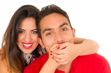 Close up of happy couple isolated on white background. Attractive man and woman being playful, woman putting her hands over his boyfriend mouth