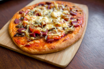 Pizza with salami, tomatoes, cheese on a wooden board