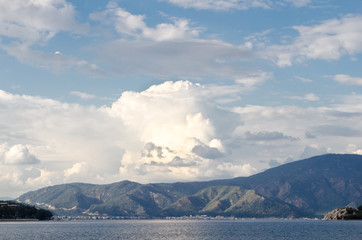 Summer panorama of the beach at sea and high mountains against the background of yachts and ships. Island in the middle of the sea. Ocean and islands