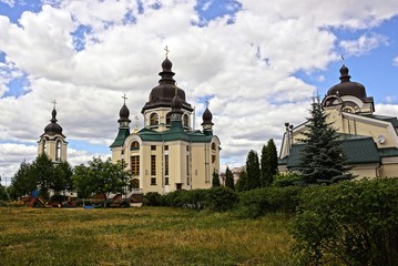 монастыри и церкви в зелёном парке на фоне неба и облаков
