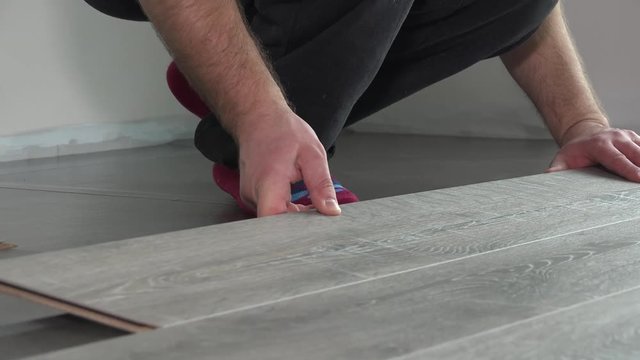 Contractor installing wooden laminate flooring with insulation