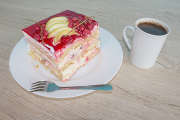 Sliced tasty cake and coffee on wooden table background. Cake with fresh red currant on the plate
