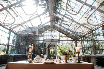 decorated table with flowers, candles and sweets in greenhouse