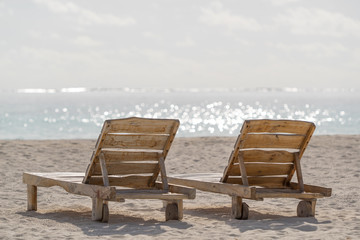 Fototapeta na wymiar Empty wooden beach chairs on the tropical beach, vacation. Traveler dreams concept
