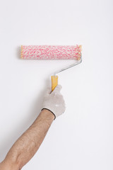 Close up of painter arm painting a wall with red paint roller