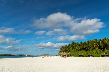 Tropical beach. Ocean waves and cloudy sky background. White sand and crystal-blue sea. Ocean water nature, beach relax. Summer sea vacation. Maldives islands sea background