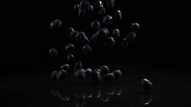 Blueberries fall on a black solid surface