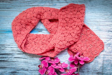 Knitted scarf, handmade, orange on a wooden table.