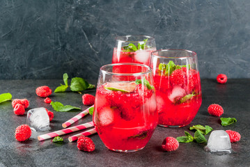 Summer refreshing non-alcoholic cocktails. Fruit drinks. Raspberry mojito lemonade with fresh organic mint and lime. On a black stone table. Copy space