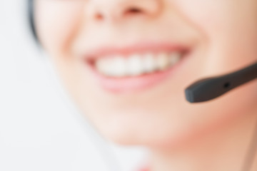 Smiling girl in the headset is working in the customer support center. Blurred image.