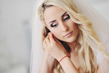 Bride's portrait: the young girl puts on ornament, an earring