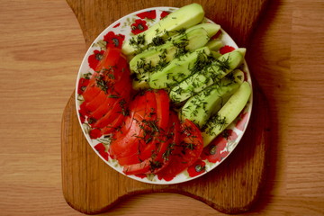 Cucumbers with tomatoes are sliced on the table