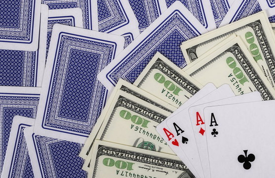  Hundred dollar bills and four ace cards on green background and texture