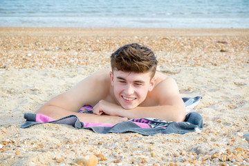 Fototapeta na wymiar Teenage boy laying on a stoney beach