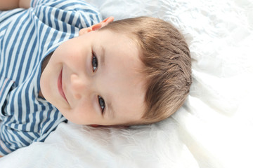 niño feliz sonriendo tumbado en cama