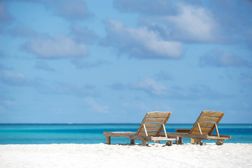Empty wooden beach chairs on the tropical beach, vacation. Traveler dreams concept