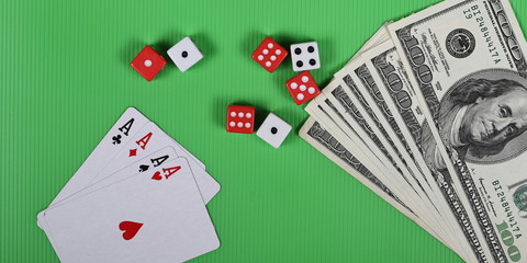 Gambling dice, four aces and dollar bills on green background and texture