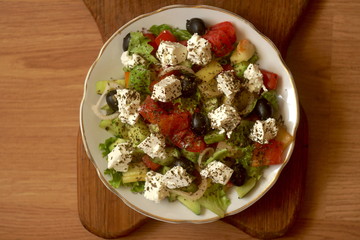 fresh healthy greek salad in plate on wooden table