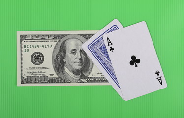 Hundred dollar bill and ace cards on green background and texture