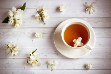 Cup of tea with jasmine flowers on a wooden background