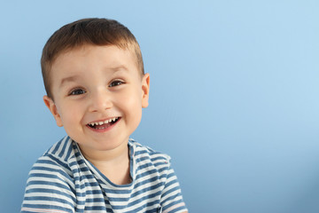 niño pequeño sonriendo en un fondo azul con espacio para copia - 164318153