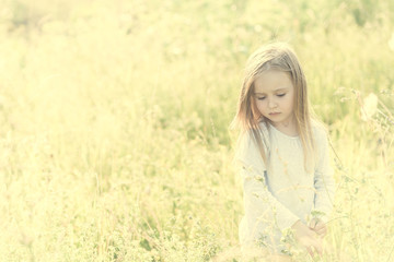 child in field among flowers and herbs, smiling