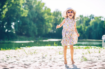 Naklejka premium Little beautiful girl lies in the sand on the beach