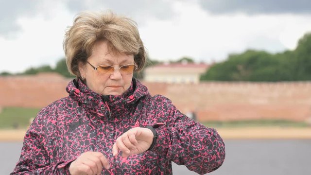 Black smartband. Outdoors adult woman looks at the results of physical activity using the smart fitness tracker. Slow motion