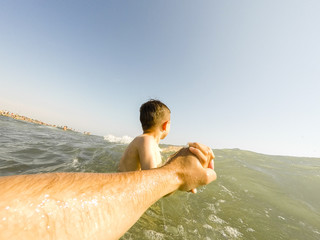 Child holds the father's hand. Playing at sea. Original Point of View
