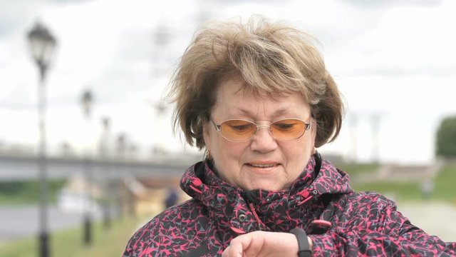 Black smartband. Outdoors adult woman looks at the results of physical activity using the smart fitness tracker. Slow motion